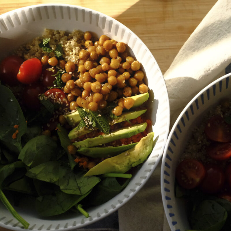 Frühlingshafte Quinoa-Bowl mit Avocado, Babyspinat, Kichererbsen und frischer Minze in einer hellen Schale serviert