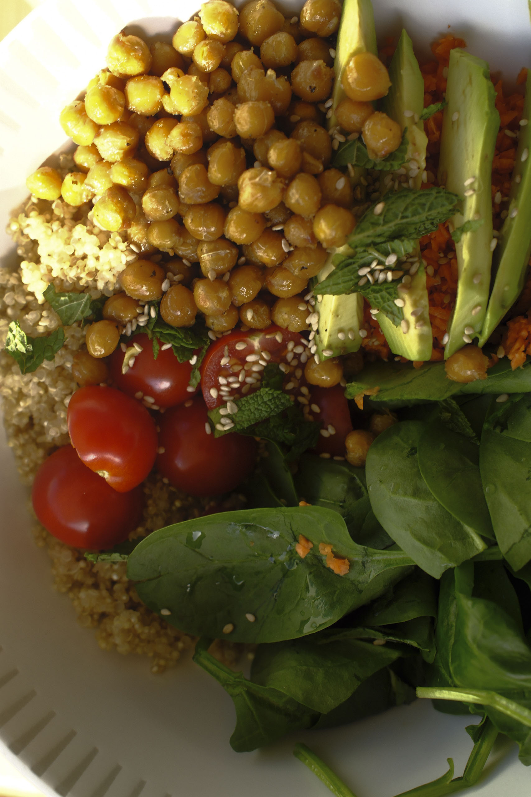 Nahaufnahme einer frühlingshaften Quinoa-Bowl mit Avocado, Kichererbsen, Minze, Spinat und frischem Gemüse, reich an Ballaststoffen, guten Fetten und pflanzlichem Eiweiß